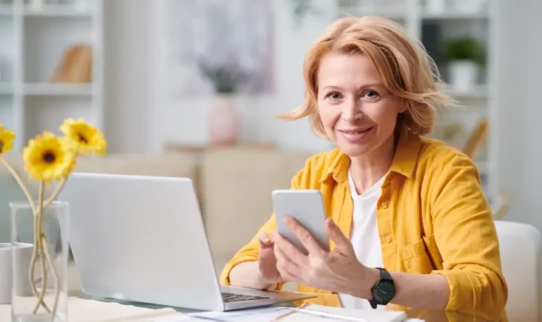 mulher com iphone na mão e laptop